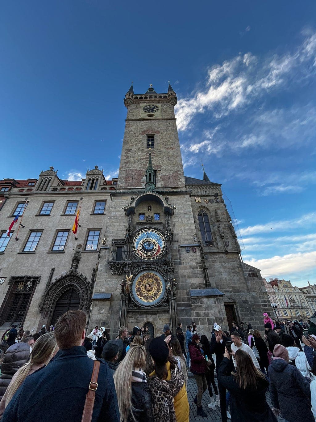 An ornate astronomical clock tower above a busy square