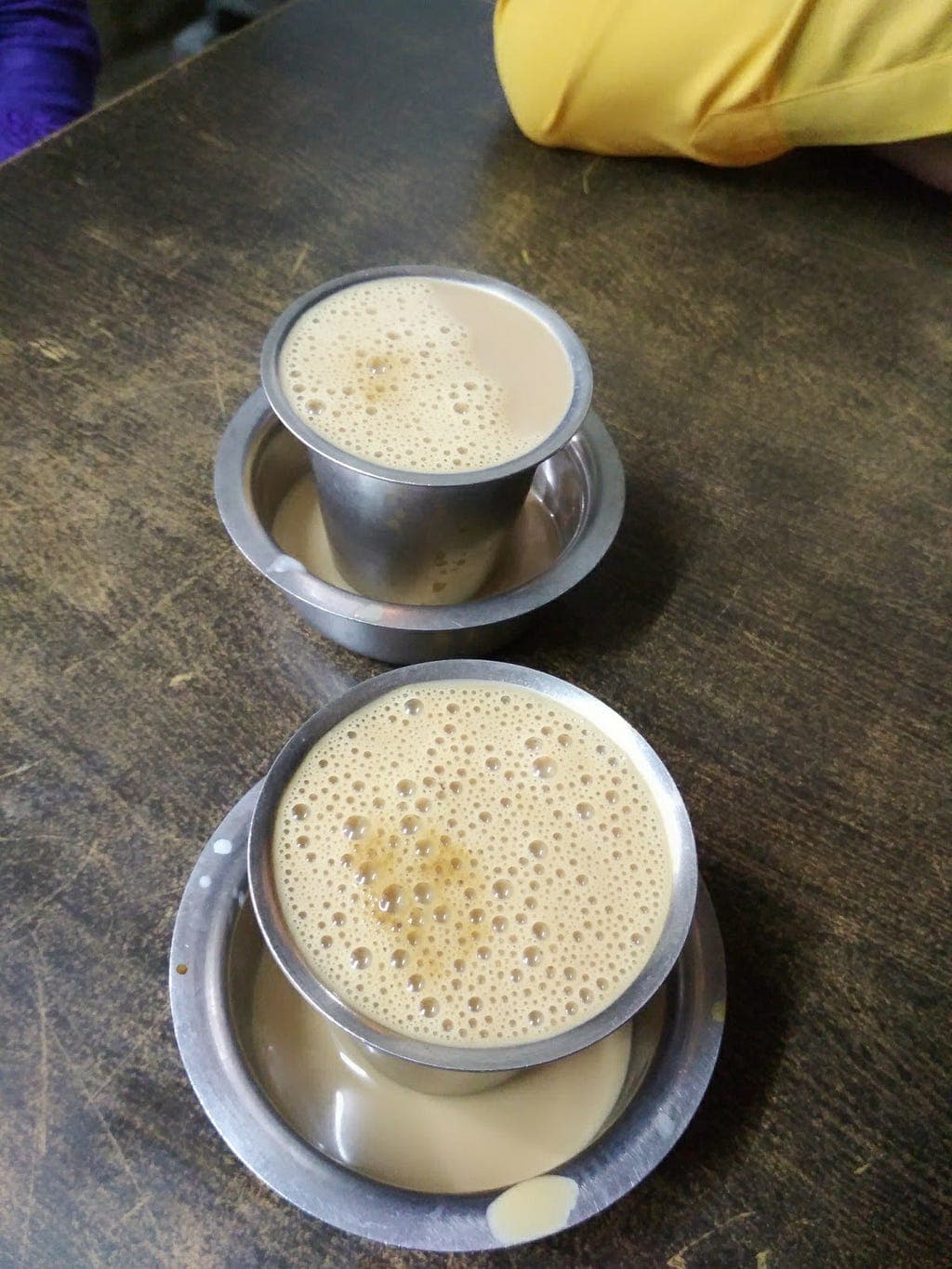 Two steel cups filled with frothy tea