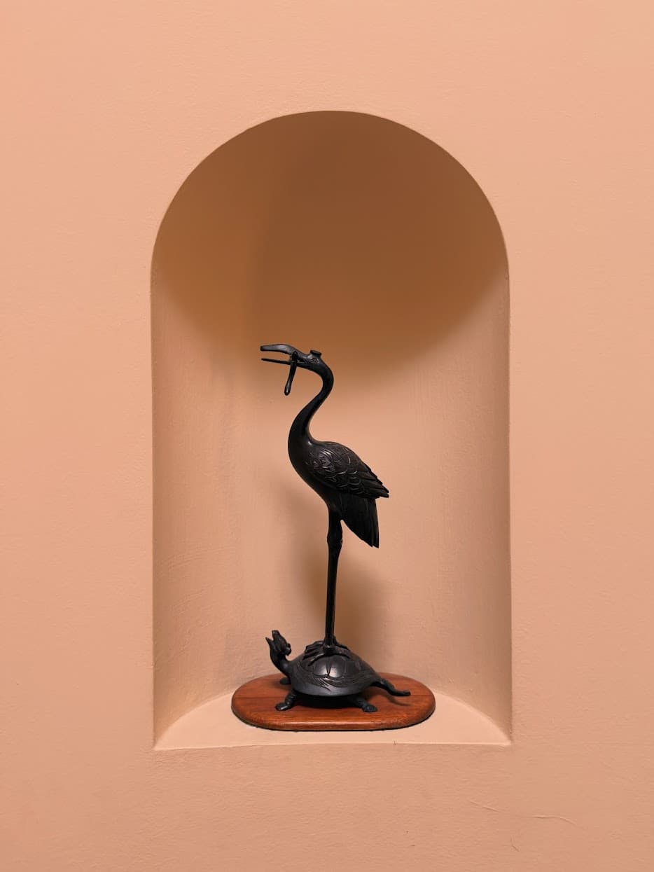 A black bird perched on a small turtle sculpture in a peach alcove