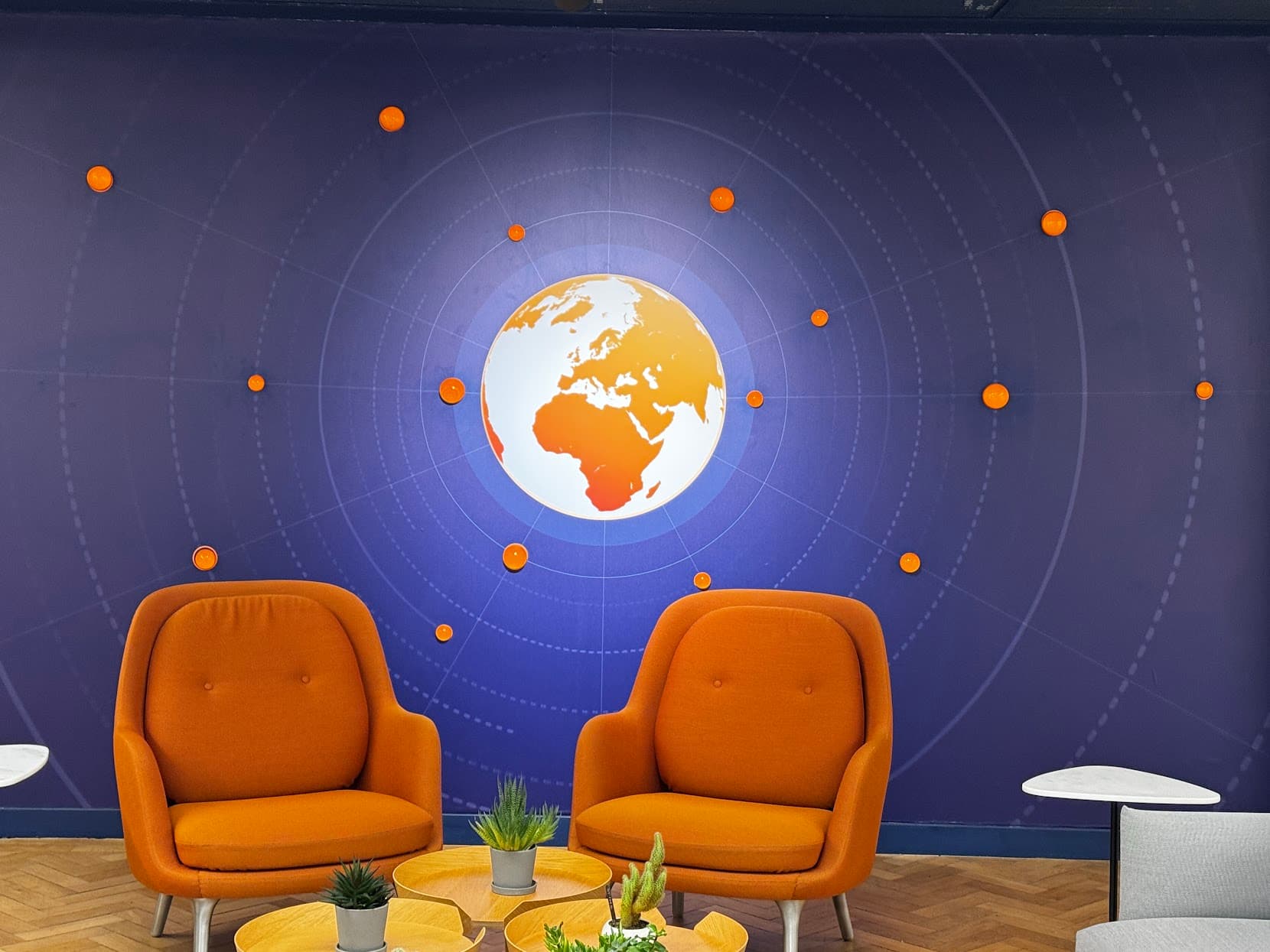 Two orange chairs beneath a glowing map of the world