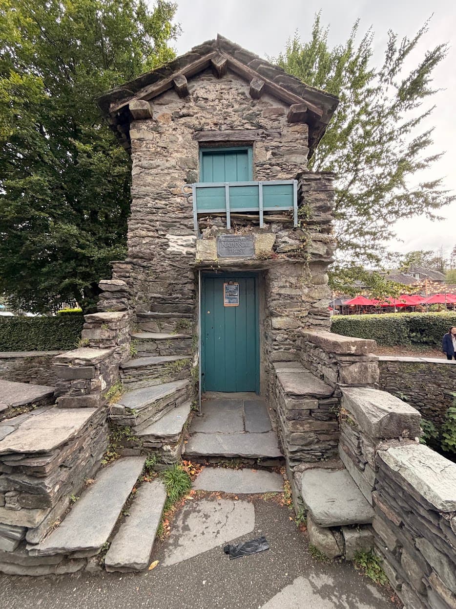 A tiny historic stone building with teal wooden doors