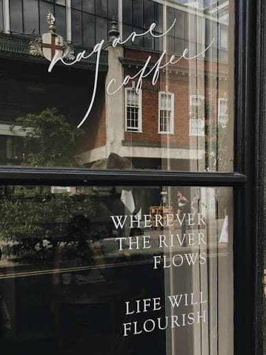 Cafe window lettering that reads wherever the river flows, life will flourish